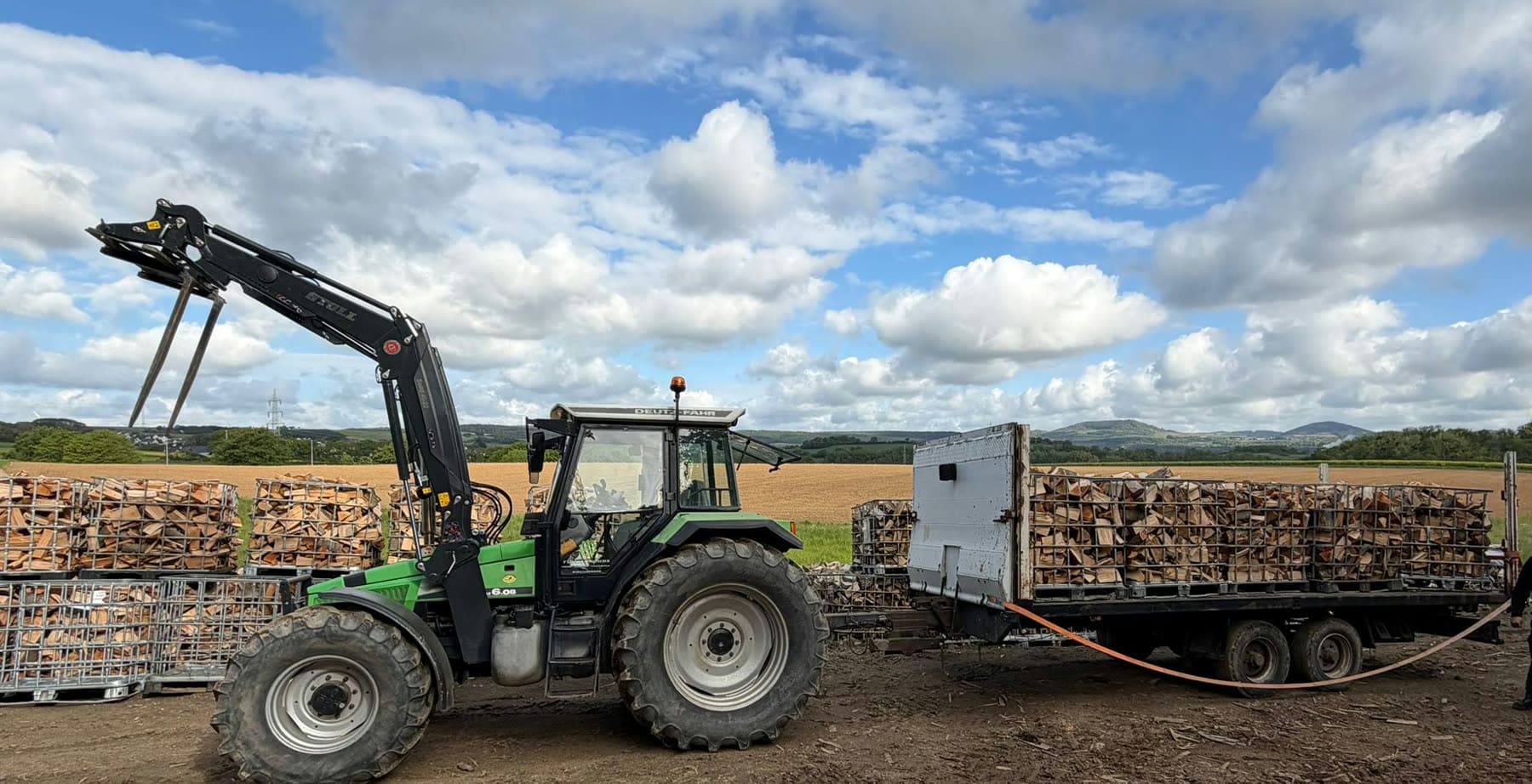 Traktor mit Brennholz-Gitterboxen bei Lohnarbeiten